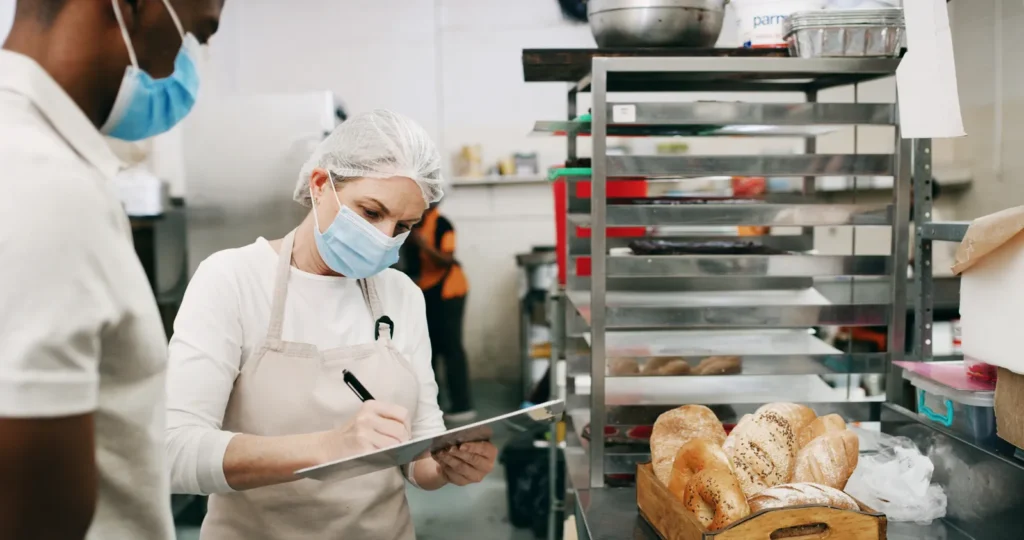 Addetta al controllo igienico con cartellina che compila una checklist in una cucina professionale