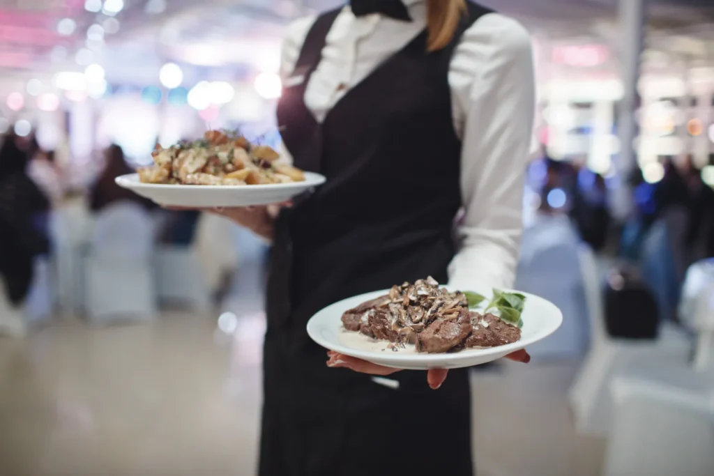 Cameriera di un servizio catering con due piatti in mano durante un evento