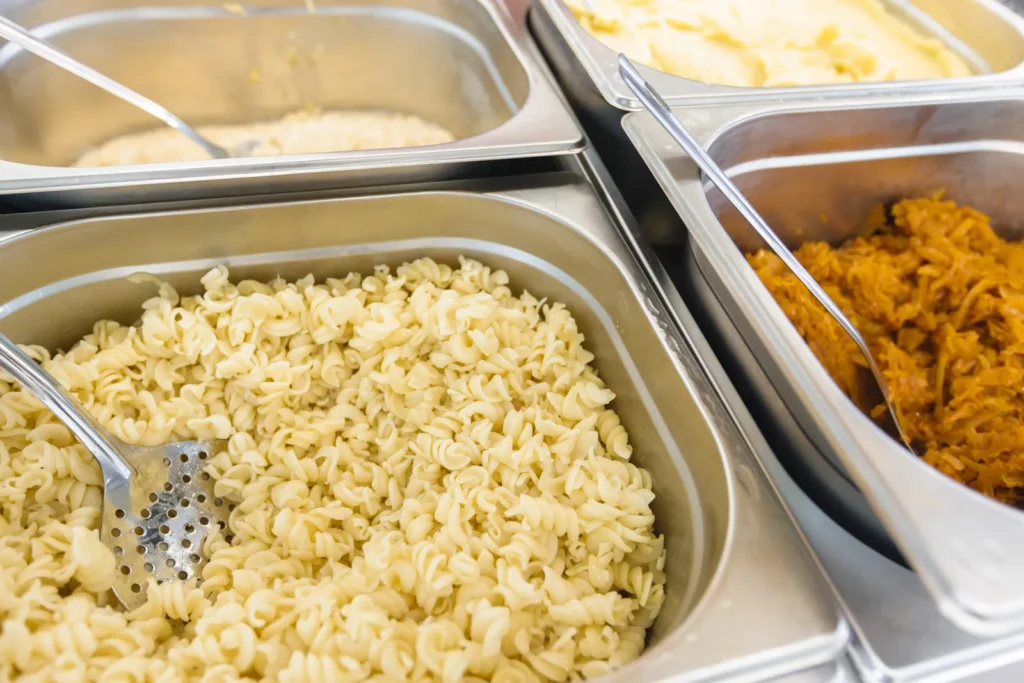 Linea self-service di una mensa con vaschette gastronorm di pasta e verdure